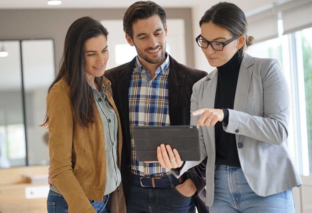 A buyer reviews a printed home listing beside a laptop and property comparison notes.