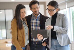 A buyer reviews a printed home listing beside a laptop and property comparison notes.